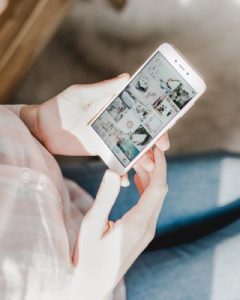 A woman holding a smartphone, while sharing things on social media